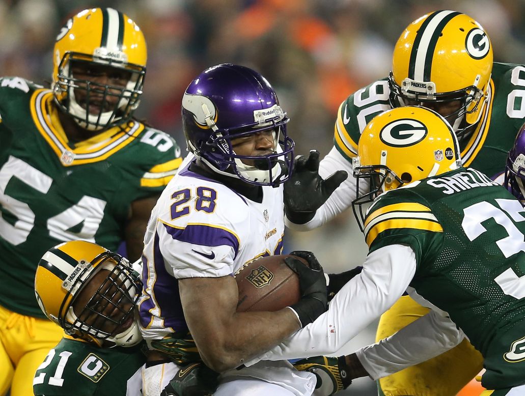 Running back Adrian Peterson of the Minnesota Vikings is tackled by several Green Bay Packers during an NFC Wild Card playoff game Saturday, January 5, in Green Bay, Wisconsin.