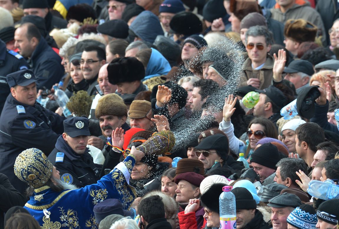 An Orthodox priest splashes people with holy water in Constanta City on Sunday.