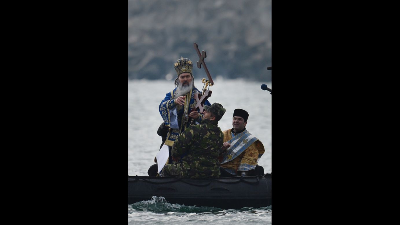 A priest throws a wooden cross in the Black Sea during a service in Constanta City, Romania, on Sunday.