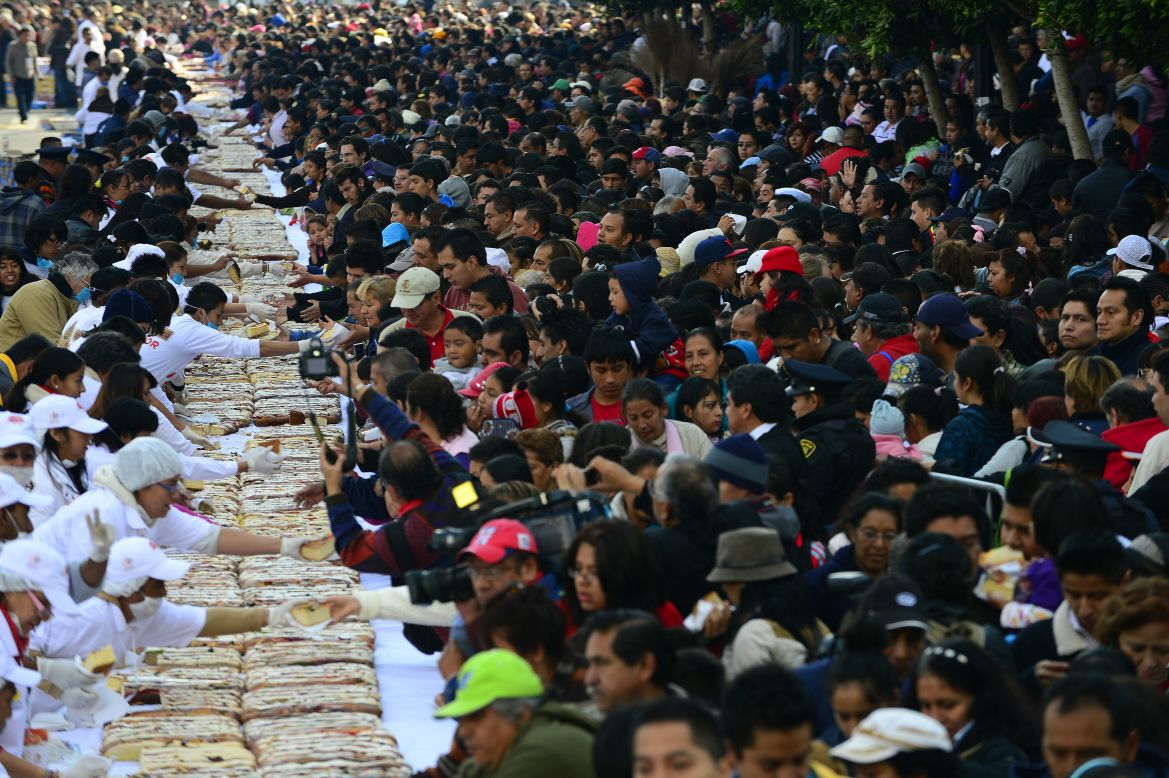 People gather to get a piece of the traditional "Rosca de Reyes," or Mexican epiphany bread, in Mexico City on Thursday, January 3, The world's biggest "Rosca de Reyes," weighing 10 metric tons, was distributed among 200,000 people at Zocalo Square in the Mexican capital.  