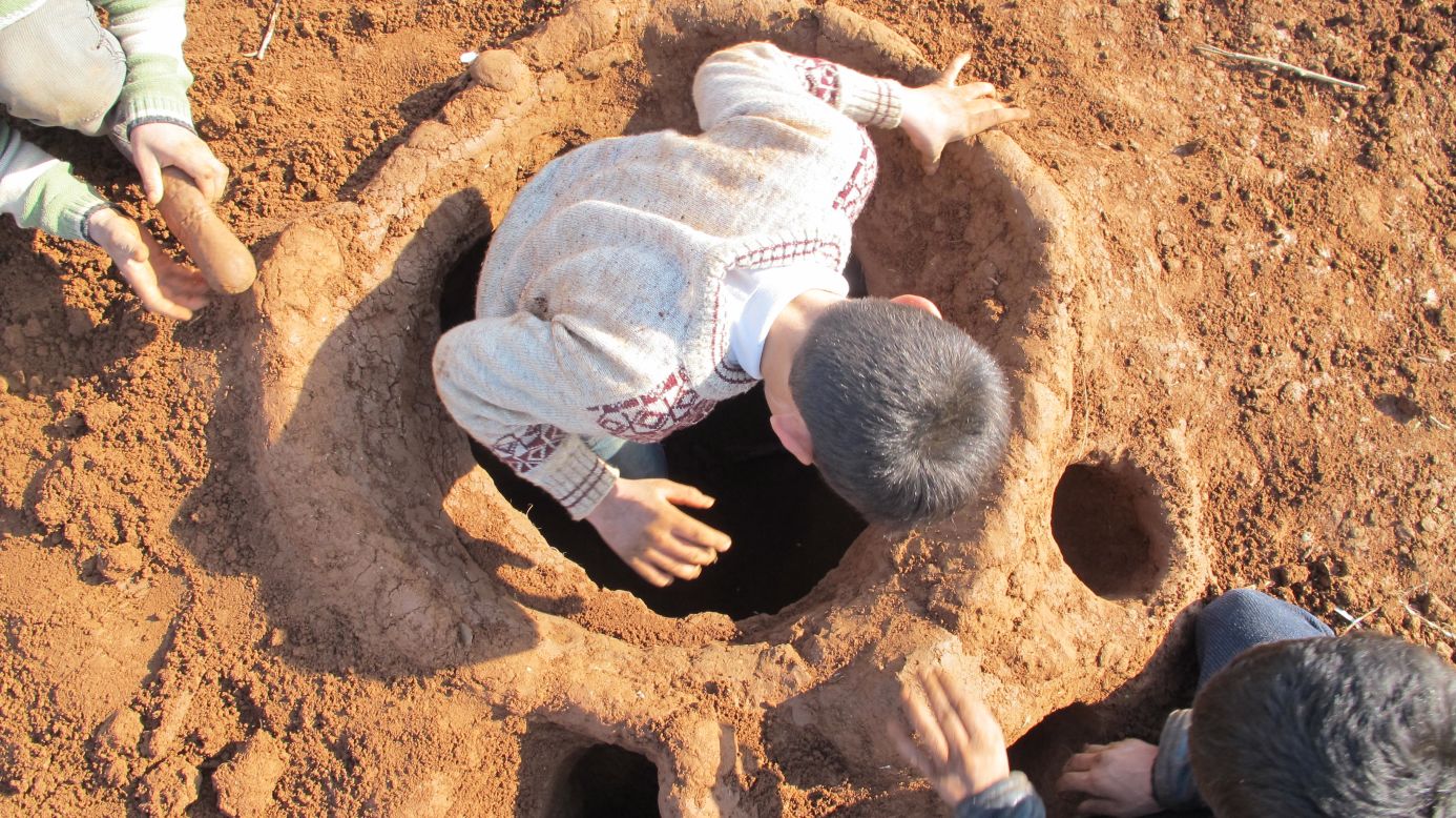 In the Bab al-Salam camp on the Syrian-Turkish border, Syrian refugees try to carry on their lives through the bitter winter. Muhammad Zafir, 13, steps inside the hole he dug with two of his friends: a bomb shelter they have made for children.