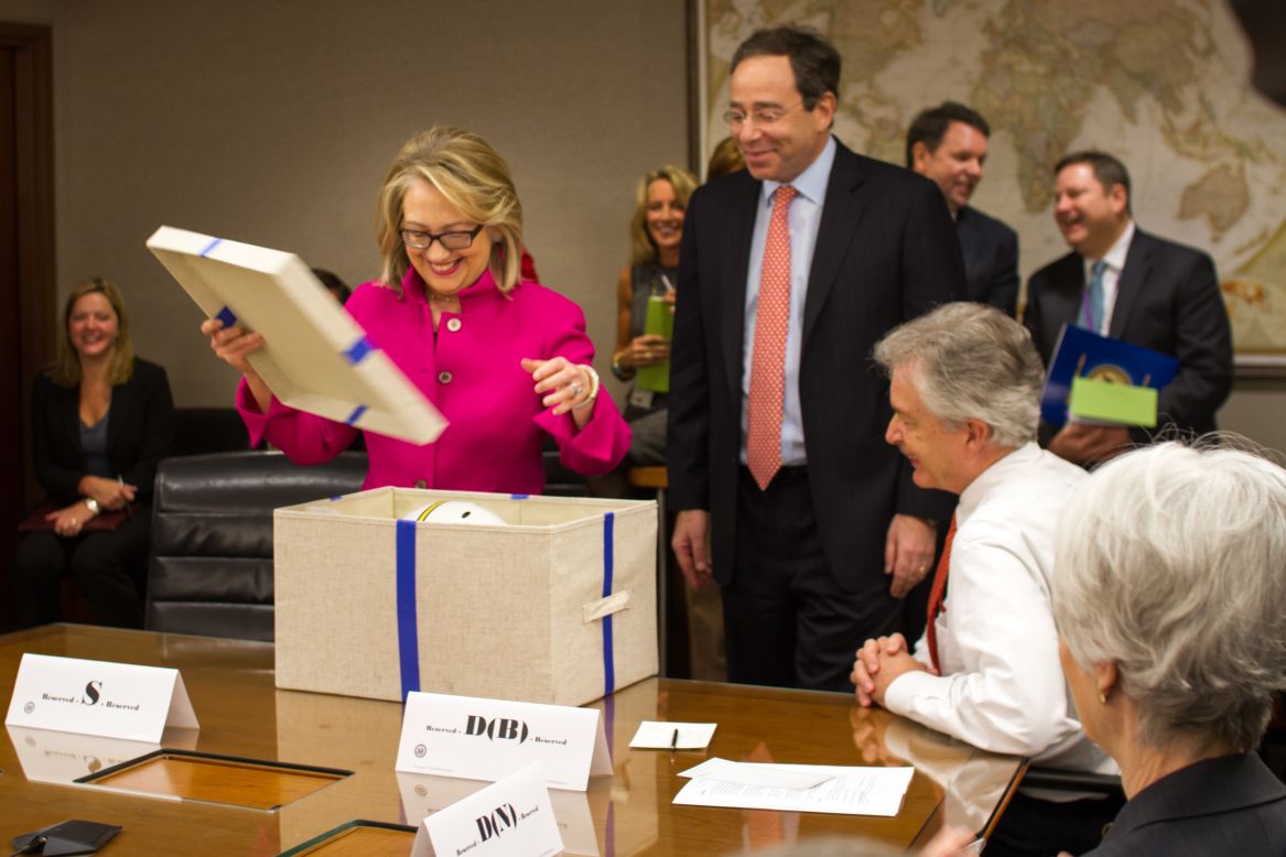 Secretary of State Hillary Clinton opens a gift from senior managers at the State Department upon returning to work on Monday.  She returned to work after being hospitalized for the flu, a concussion, and blood clot.  