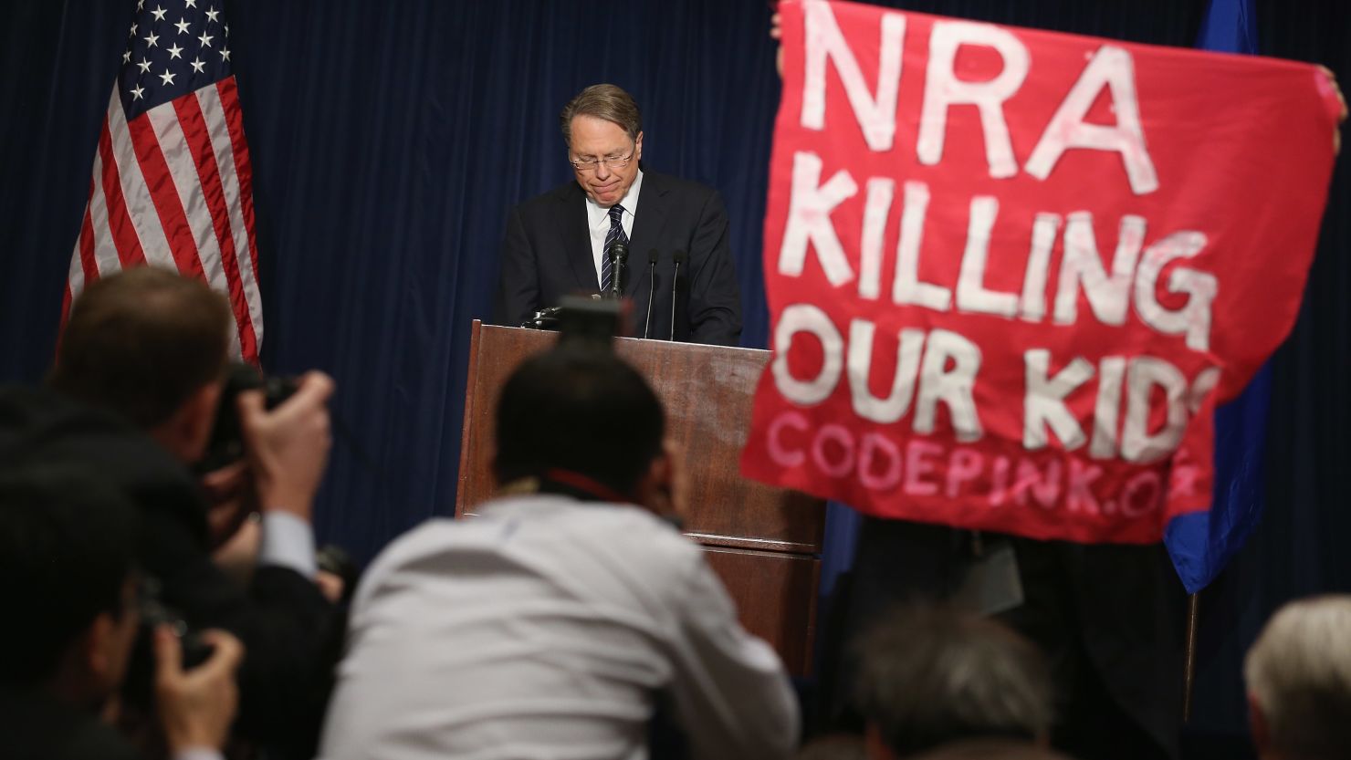 An anti-gun activist holds up a banner as NRA leader Wayne LaPierre talks about the Newtown, Connecticut, school slaughter.