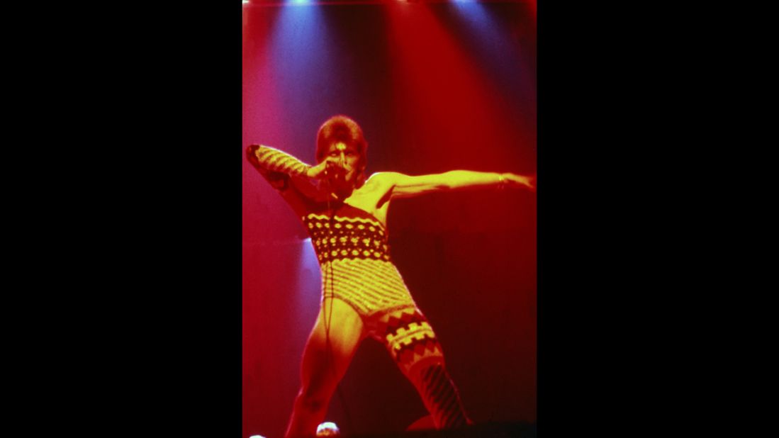 Bowie performs onstage in 1973 wearing makeup and a costume that covers only one leg and one arm. 
