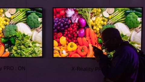 A man talks to his phone with Sony Bravia HDTV televisions in the background.