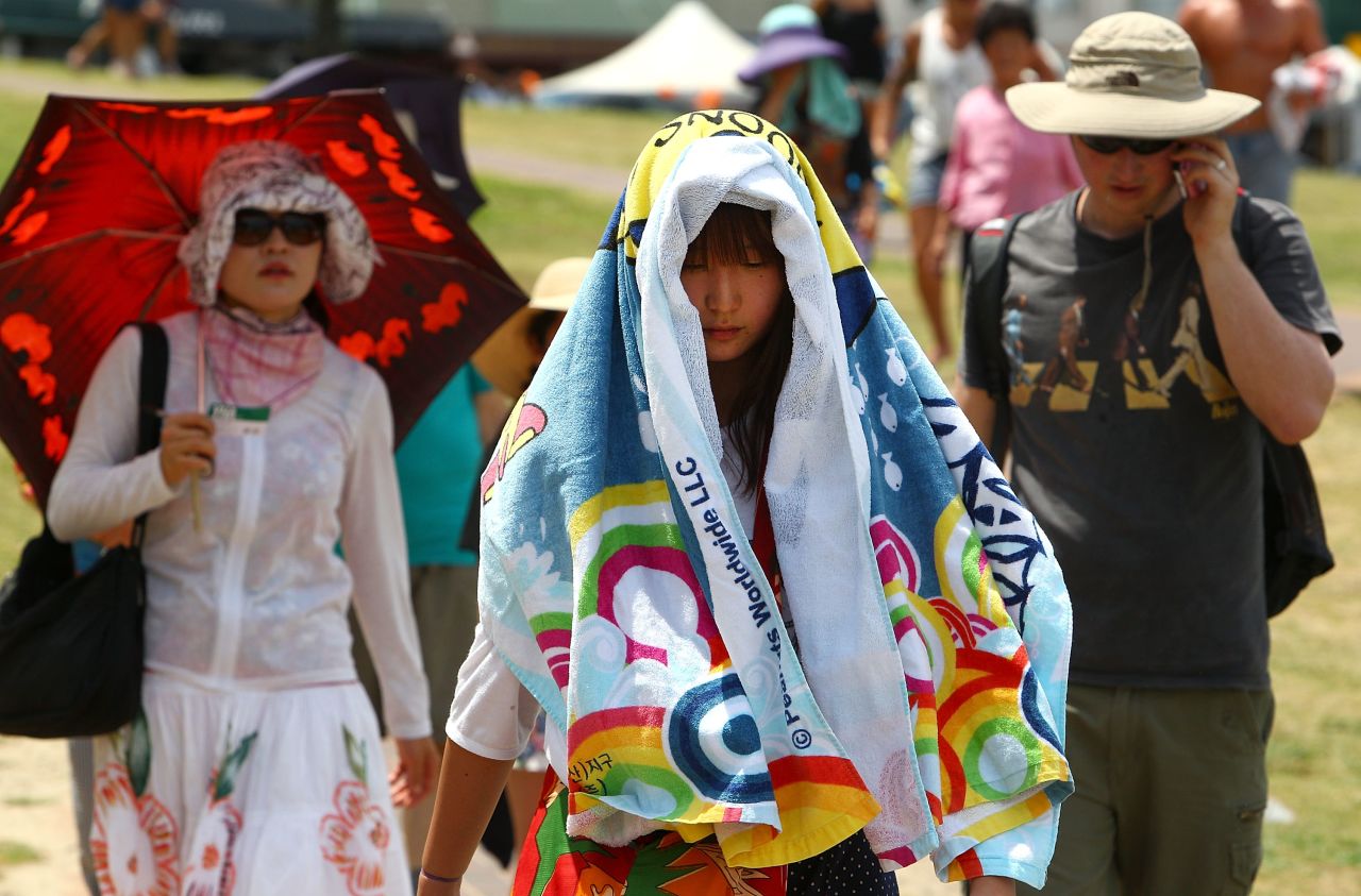 Tourists cover themselves with towels to protect themselves from the sun on one of the hottest days on record.
