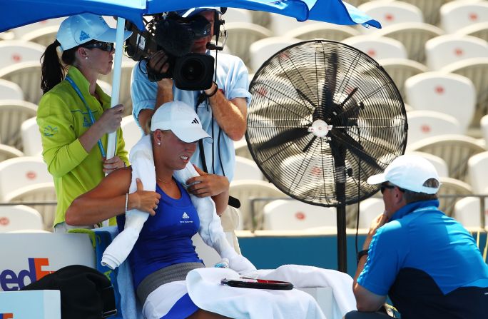 Officials decided not to suspend play despite scorching heat. Here, world No. 10 Caroline Wozniacki makes use of a fan and an ice towel during a break in her match.