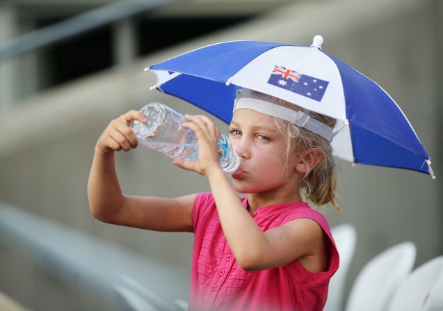A young fan takes on water under the shade of their umbrella at Sydney Olympic Park.