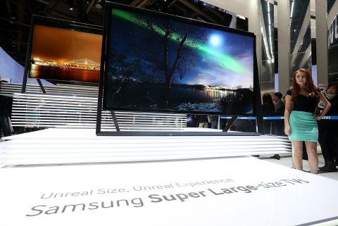 A model stands next to a display of new large-format Samsung televisions at Samsung's Consumer Electronics Show booth in the Las Vegas Convention Center.