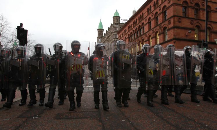 Police in riot gear march behind loyalist protesters on Saturday.