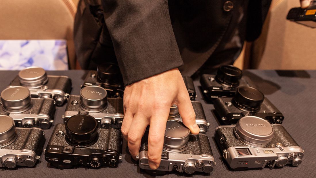 Members of the press take a peek at Fujifilm's new high-end compact cameras, the X100S and X20, on Monday.
