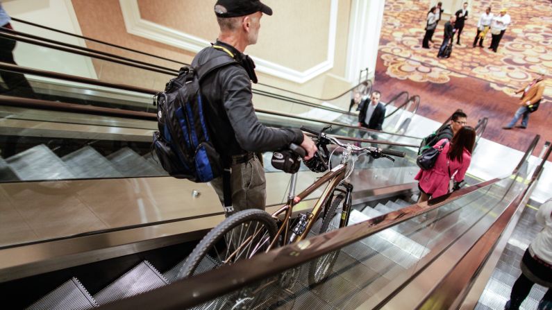 A man takes his bike down an escalator Monday at the Las Vegas Convention Center.