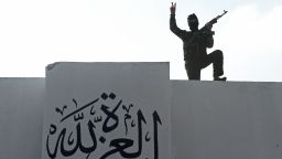 A Syrian member of the Committee for Promotion of Virtues and Prevention of Vice gestures near a freshly painted wall reading 'Glory to God' at their headquarters in al-Bab, northern Syria, on November 21, 2012. The committee was created to fight abuses and crimes committed by members of the Free Syrian Army (FSA) only, and has 80 elements recruited outside the FSA. The rebels faced growing criticism, particularly after a video was posted on YouTube earlier in November, appearing to show opposition fighters beating and executing soldiers after attacks
