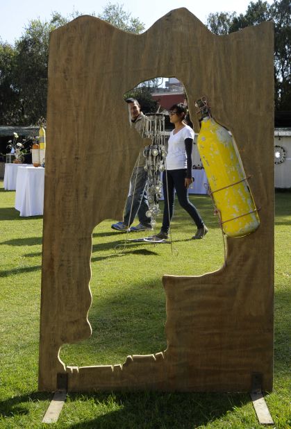 A visitor walks past an artwork made with an oxygen cylinder and plywood. 