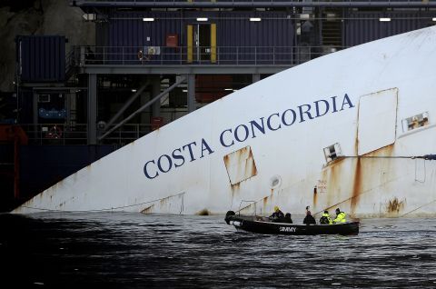 Workers in a small boat pass by the Costa Concordia on Monday, January 7. <a href="http://www.cnn.com/2012/01/14/europe/gallery/italy-ship/index.html">See photos from the shipwreck in 2012.</a>
