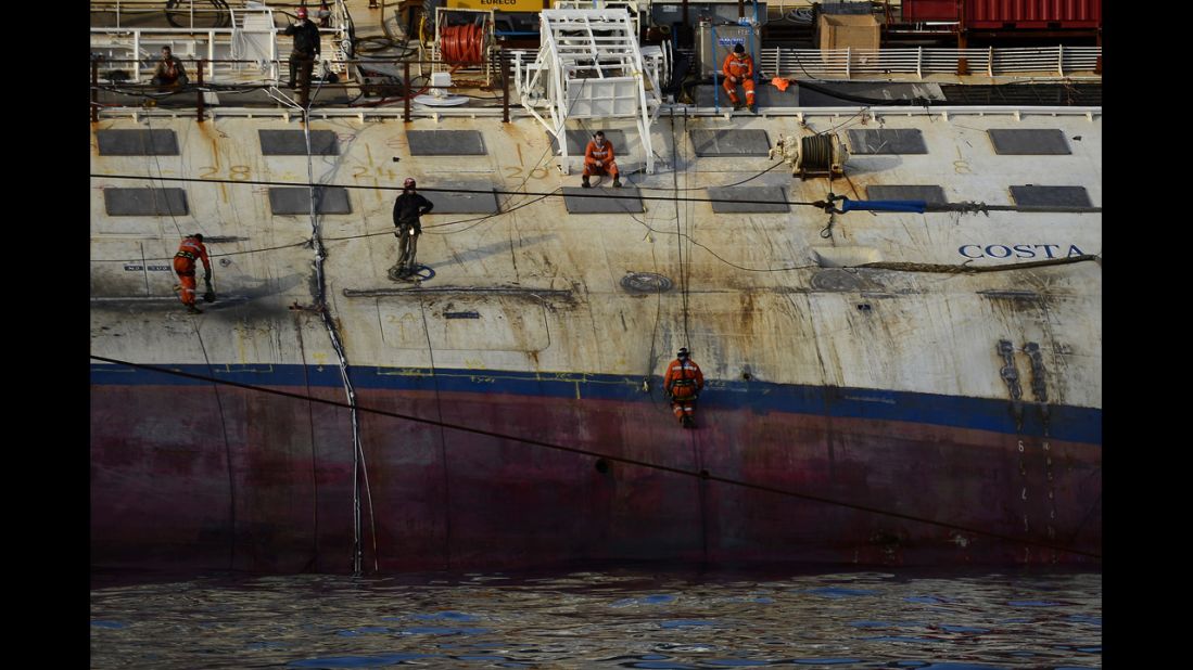 Workers stand on the Costa Concordia cruise ship on Tuesday, January 8.