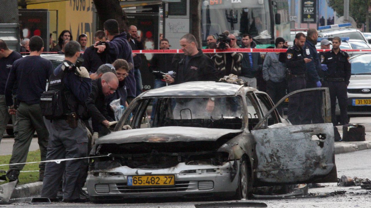 Investigators look at a damaged car after it exploded near the Israeli defence ministry in Tel Aviv on January 10, 2013.