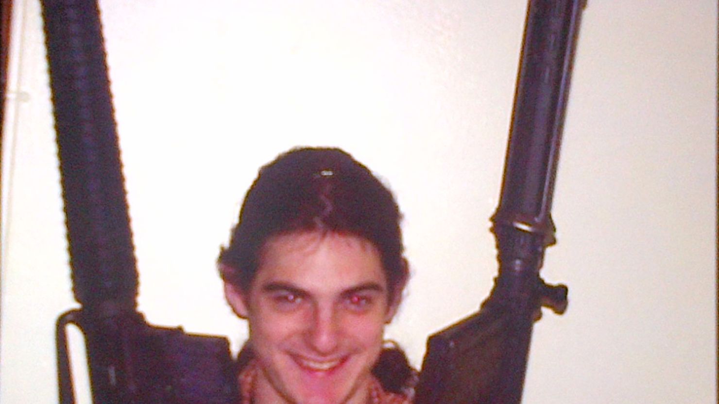 A photo shows suspect Aaron Greene posing with two guns. 