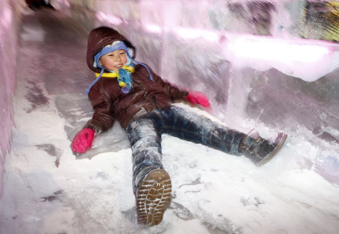 A young child slides down an ice slide at the opening ceremony of the Harbin festival on Saturday, January 5.