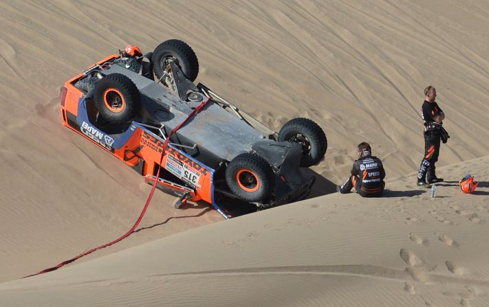 Robby Gordon of the United States, center, sits in the sand by his overturned Hummer on January 8.