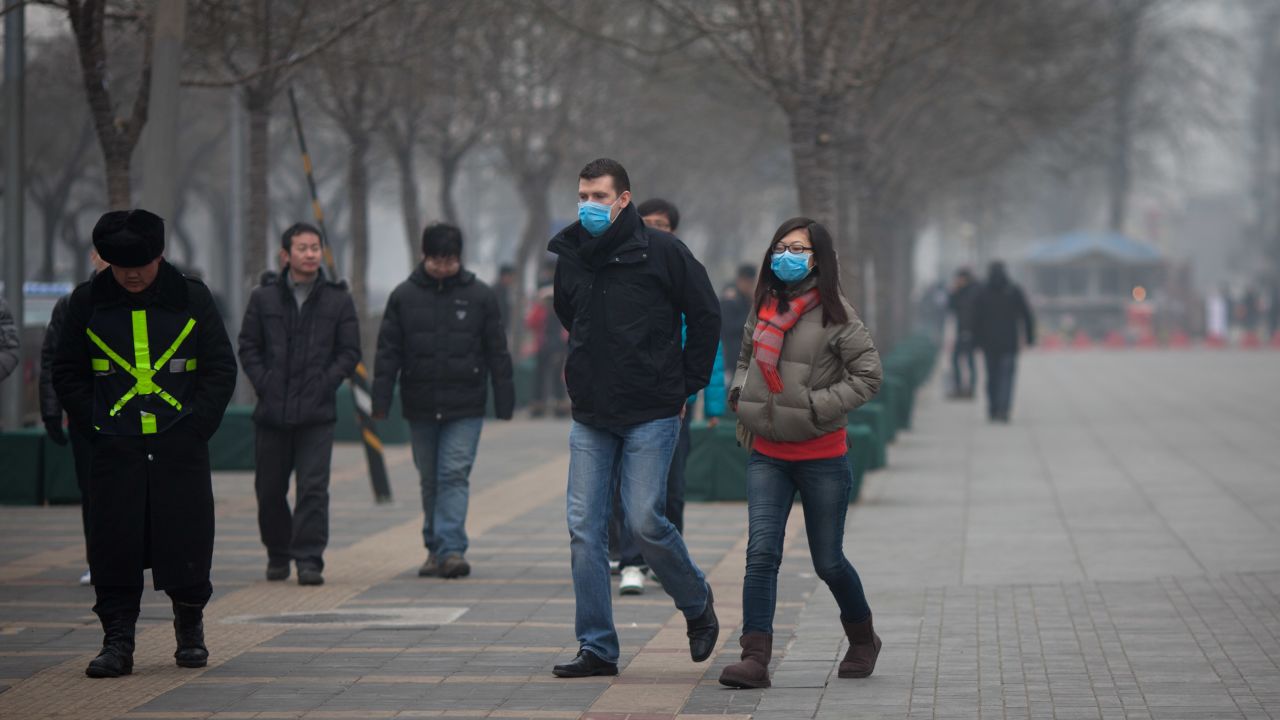 A couple wearing face masks walks in a busy shopping area during polluted weather in Beijing on January 13, 2013. 