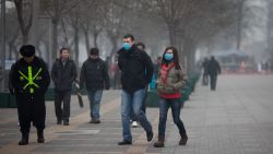 A couple wearing face masks walks in a busy shopping area during polluted weather in Beijing on January 13, 2013. 