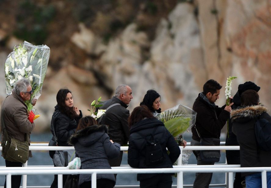 Relatives hold bouquets of flowers before throwing them into the sea on Sunday during commemorations.