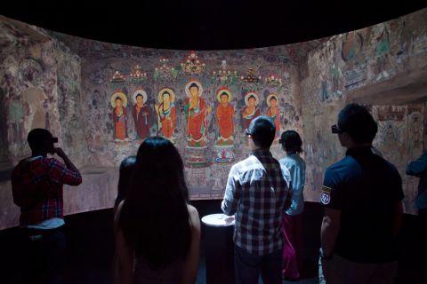 Viewers look at a digital representation of  a 1,500 year old Buddhist grotto.