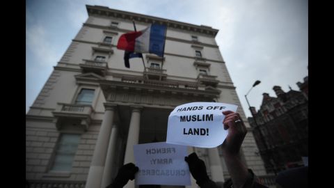 Protesters wave signs outside the French Embassy on Saturday in London.