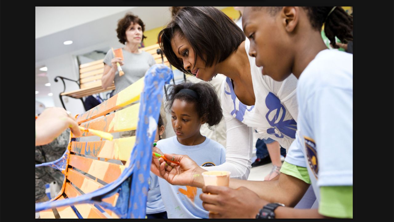 First lady Michelle Obama helps paint a bench at a service event. She and her family will be participating in National Service Day.