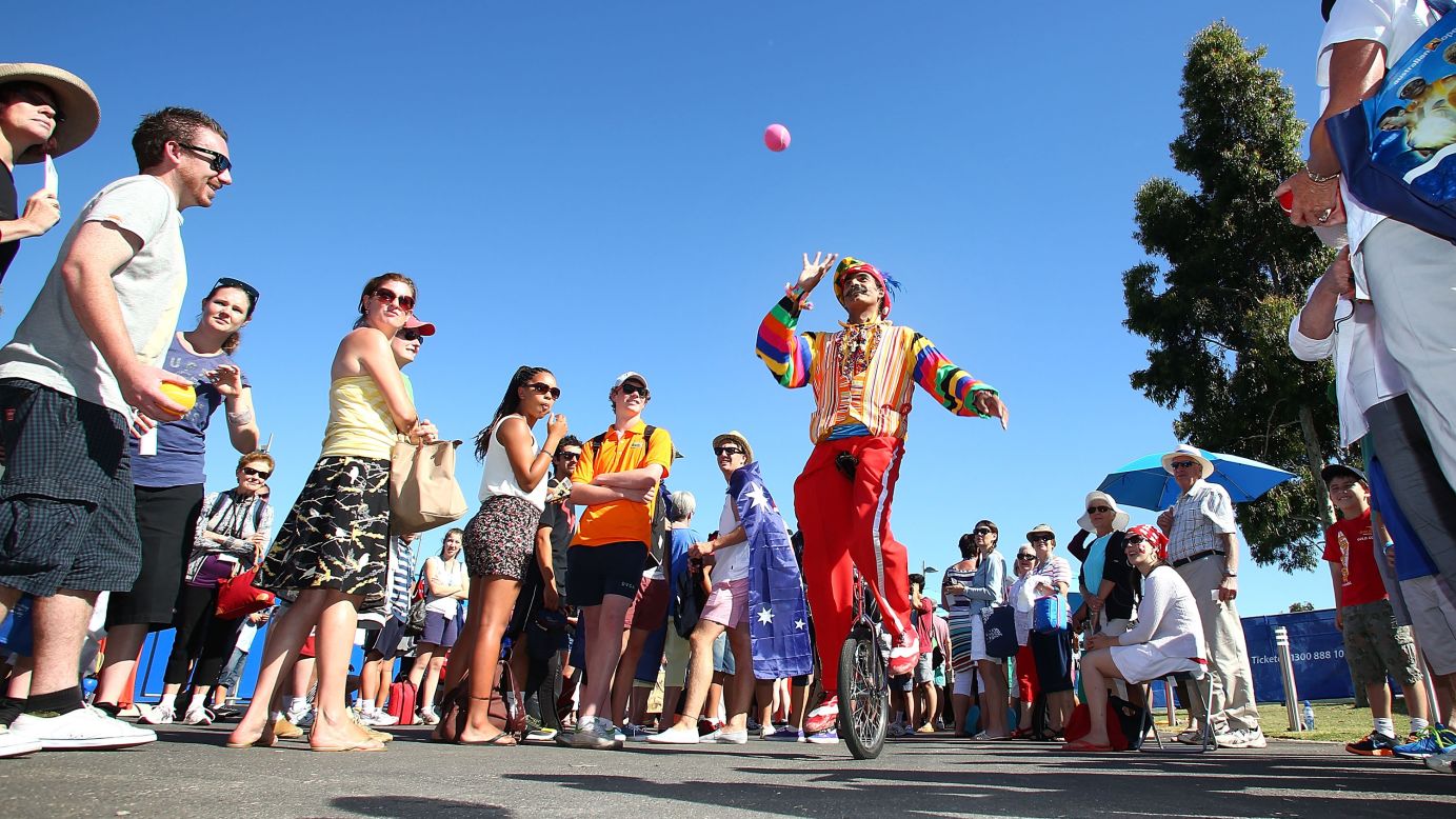 A juggler entertains the crowd as they wait to enter the grounds at Melbourne Park for Day 2 of the Australian Open.