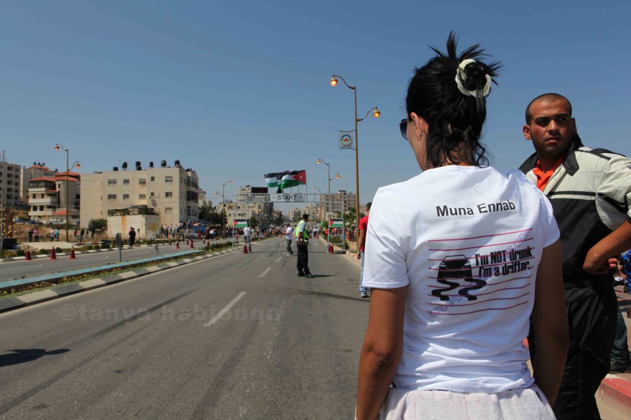 Muna Ennab watches a race in Ramallah. Her t-shirt refers to drift racing, a driving technique in which the driver deliberately oversteers and the rear wheels skid.