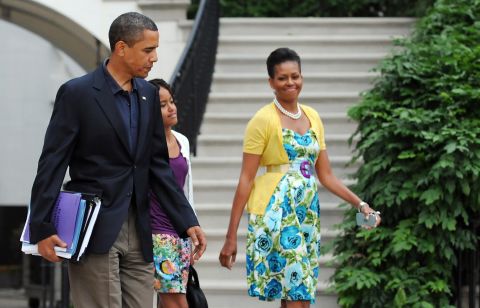 Obama has been known to wear dresses from mass retailer Talbots and accessorize them with signature pieces such as this sweater from Dear Cashmere and a belt by Sonia Rykiel, worn in July 2009, <a href="http://mrs-o.com/newdata/2009/7/5/bon-voyage.html" target="_blank" target="_blank">according to Mrs. O</a>.