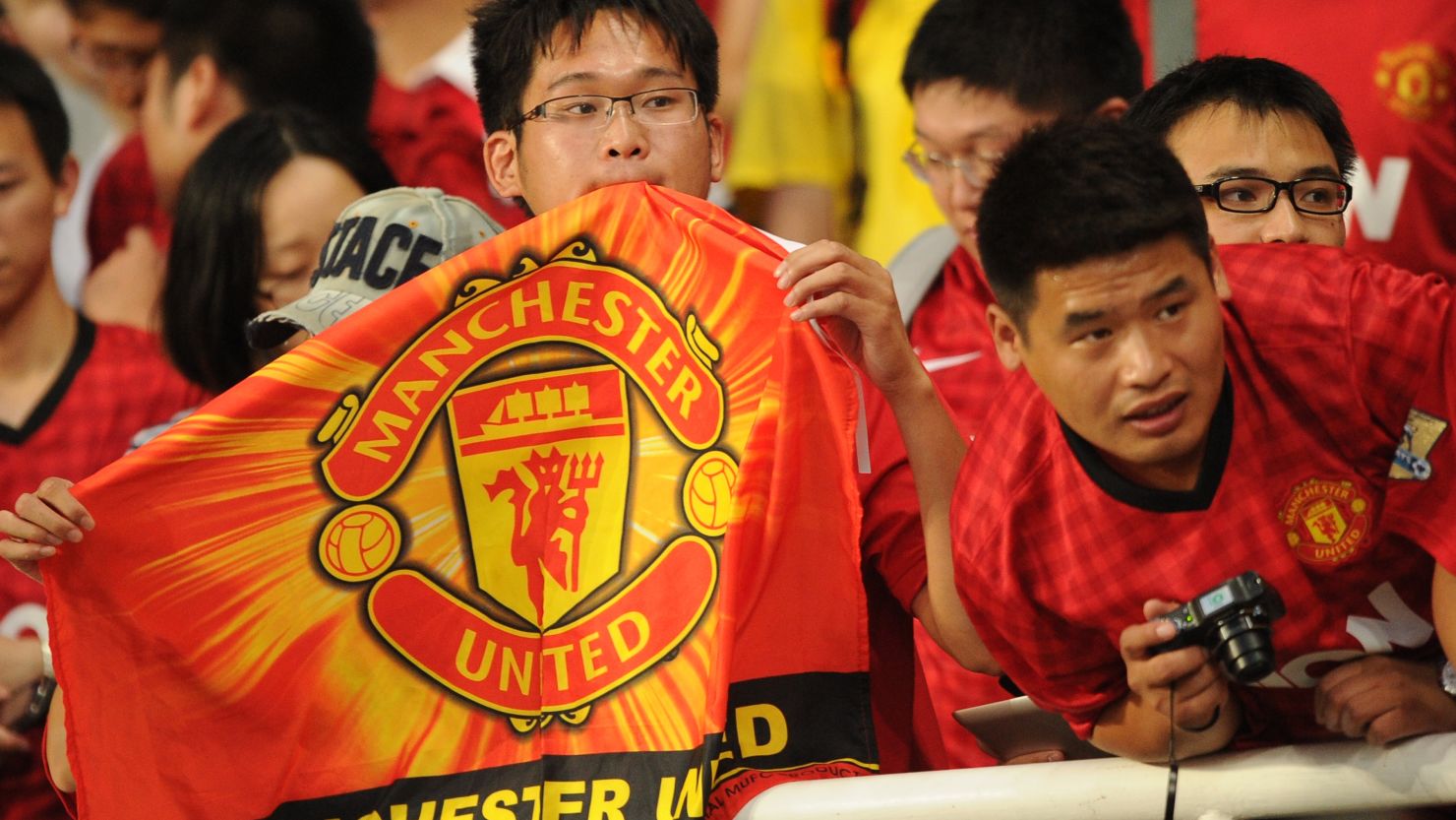 Manchester United fans look on as the team arrives for a team training session at Shanghai Stadium in Shanghai on July 24, 2012. 