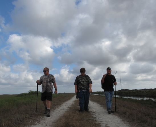 Bob Pawlowski, from left, son Coby and friend Jimmy Harper of Fort Myers, Florida, hike a dirt road in the southeastern portion of the Everglades near Miami. First-time hunters have been directed by the Florida Fish and Wildlife Commission to stay along the levees, a system of roads and canals built in the park to control water flow.