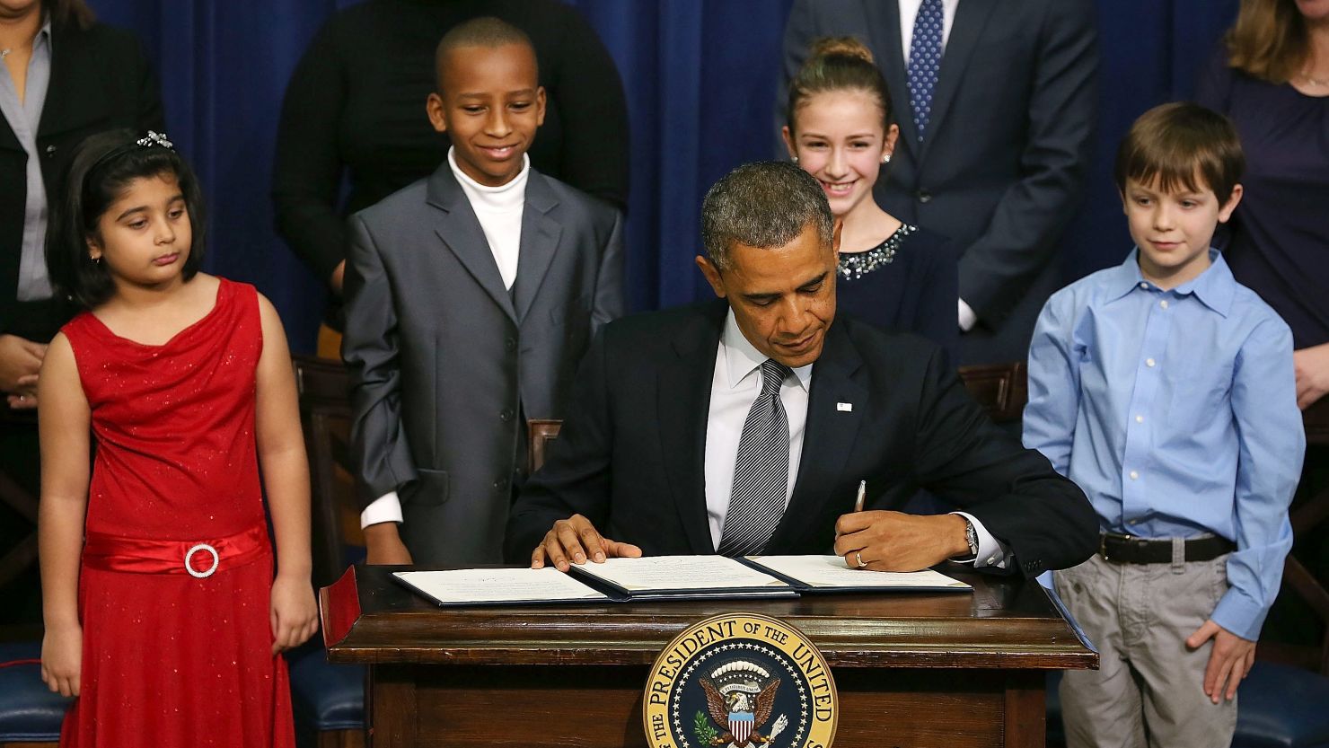 President Obama signs new gun law proposals as children who wrote letters to the White House about gun violence look on.