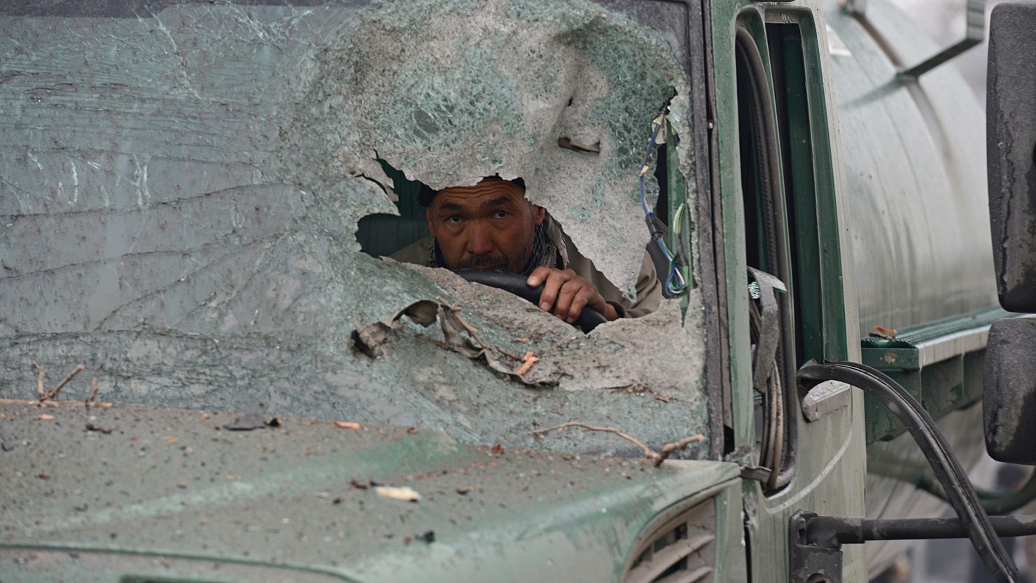 A truck driver peers through the broken windshield of his vehicle at the site of a the suicide attack on Wednesday.