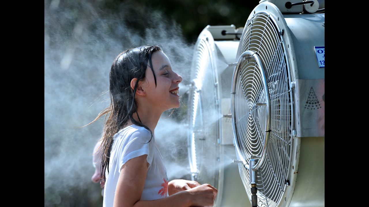 A young spectator cools off by standing in front of a water vapor machine. Temperatures reached 40 Celsius (104 Fahrenheit).