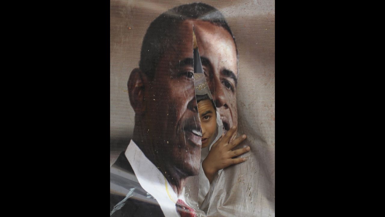 PAKISTAN: An activist of Awami Majlis-e-Amal looks through a torn poster of Obama during a protest against the reopening of the NATO supply route to Afghanistan in Quetta on July 13, 2012.