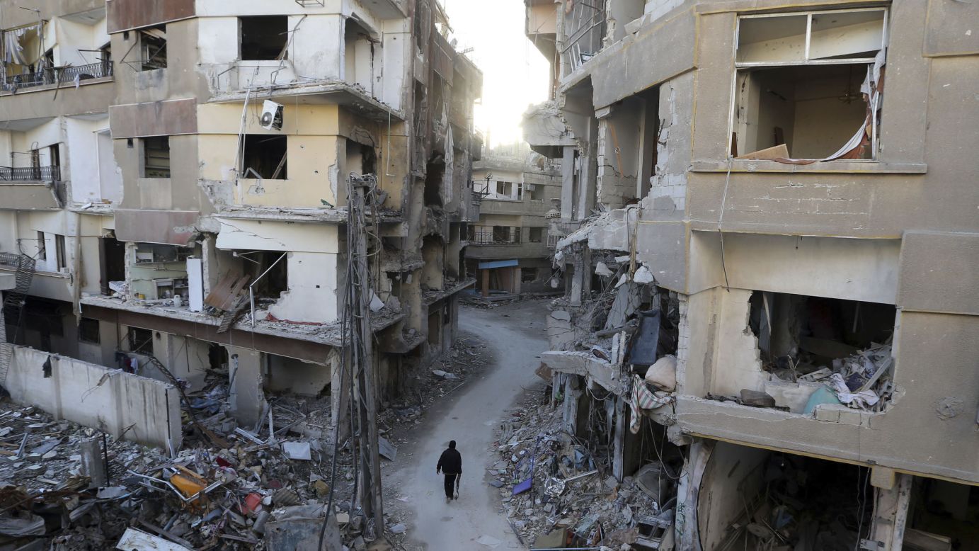 A Free Syrian Army fighter walks between buildings damaged during Syrian Air Force strikes in Damascus on January 19.
