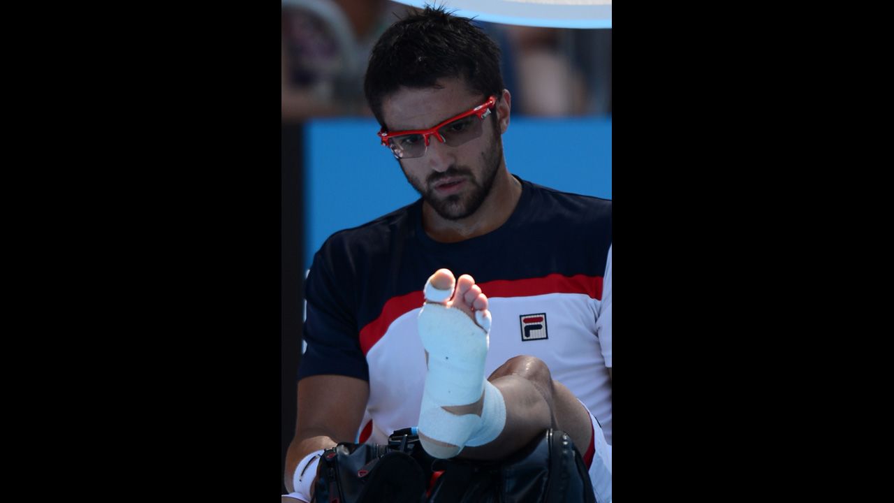 Serbia's Janko Tipsarevic looks at his wrapped foot during a break in his men's singles match against Spain's Nicolas Almagro on January 20. Almagro moved on to the next round after Tipsarevic pulled out of the match in the second set because of his injury.