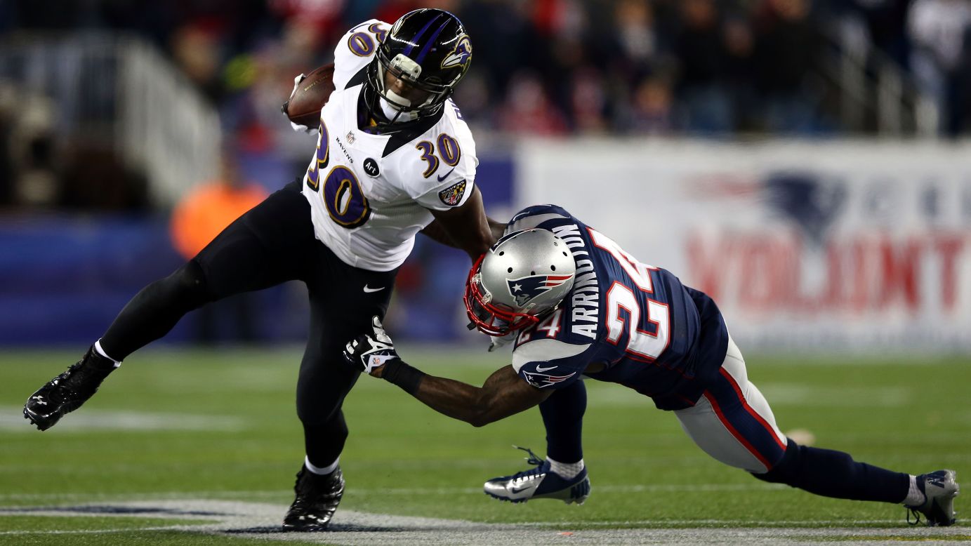 Bernard Pierce of the Ravens attempts to break a tackle by Kyle Arrington of the Patriots.