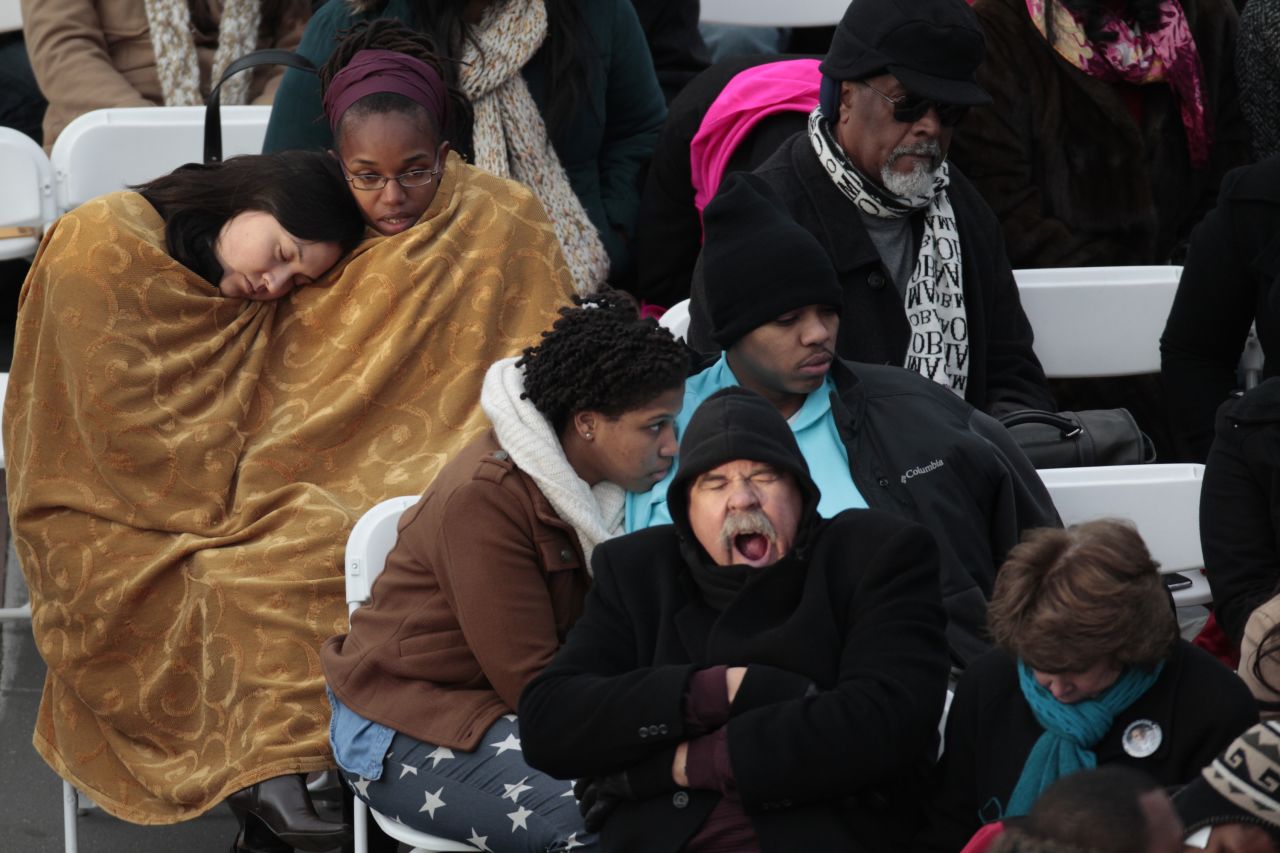 An inaugural attendee yawns while others huddle beneath a blanket Monday at the Capitol.