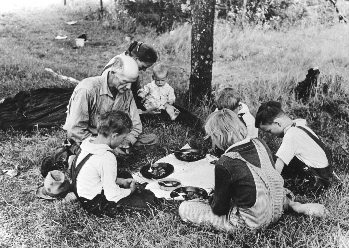 A migrant family prays before their noonday meal Oklahoma during the Great Depression. 