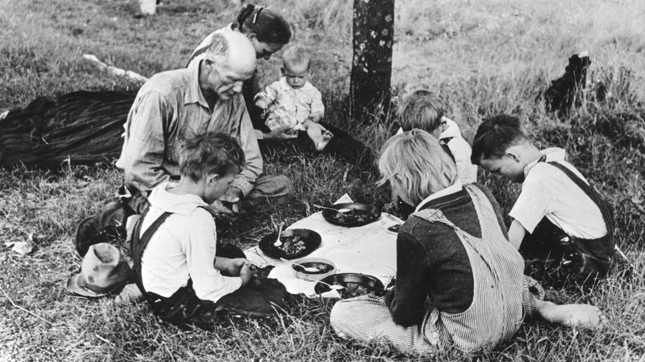 A migrant family prays before their noonday meal Oklahoma during the Great Depression.