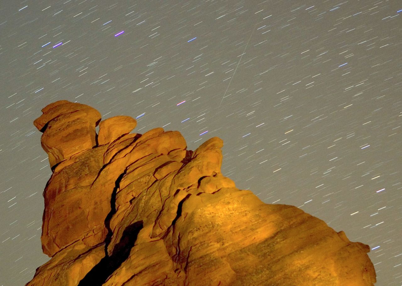 A Geminid meteor streaks diagonally across the sky -- against a field of star trails -- over a rock formation in Valley of Fire State Park in Nevada. The Geminid meteor shower happens every December, and is thought to be debris cast off from an asteroid called 3200 Phaethon.