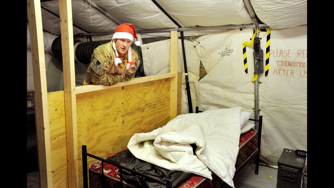 Harry shows a TV crew his sleeping area in the VHR tent while wearing a Santa hat on December 12, 2012.