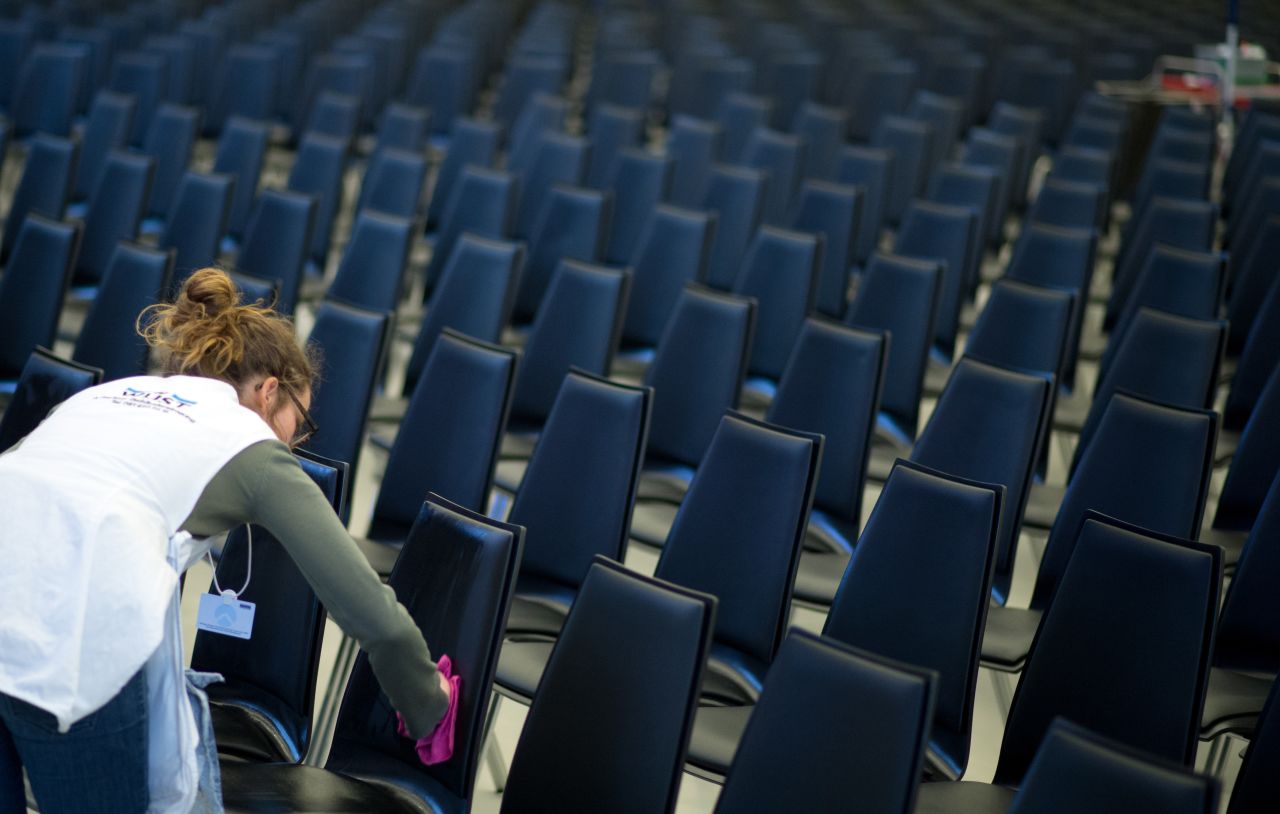 A woman cleans the chairs in the main hall at the congress center.