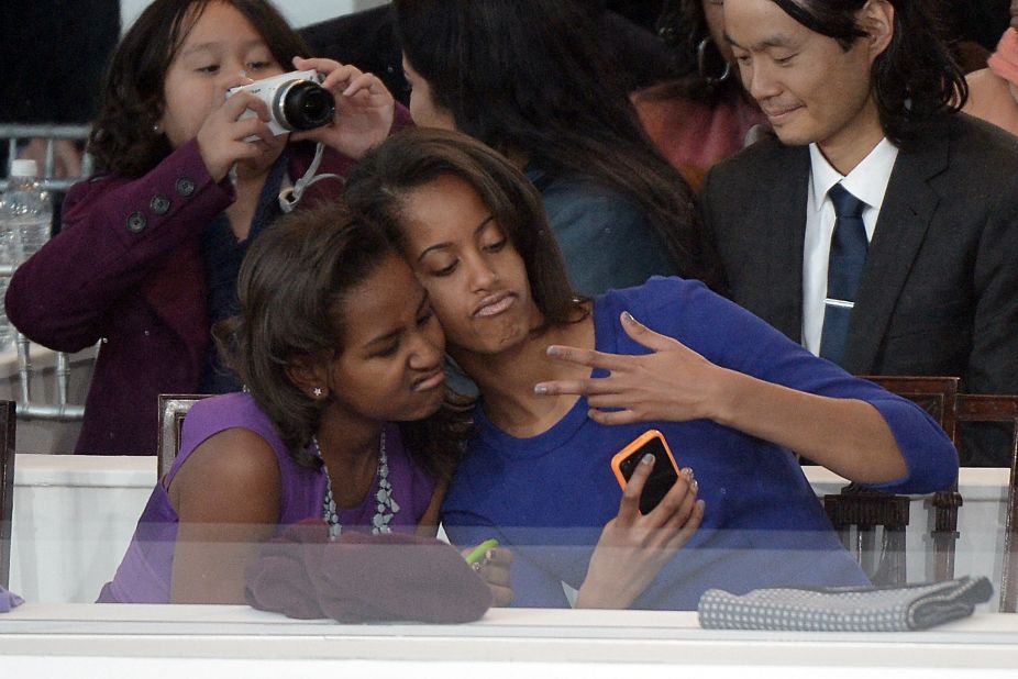 Sasha, left, and Malia Obama take a photo of themselves during the inaugural parade.