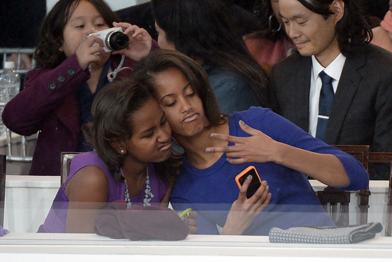 Sasha, left, and Malia take a photo of themselves during Monday's parade.